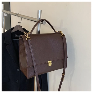 Detail of dark brown litchi pattern leather bag with gold buckle and adjustable strap
