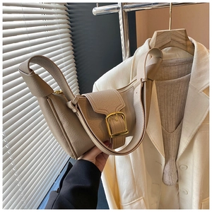 Dettaglio borsa a mezzaluna beige testurizzata con chiusura in oro e tracolla