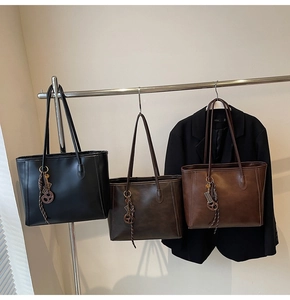 Detailed view of three vintage tote bags in black, coffee, and brown on a minimalist rack