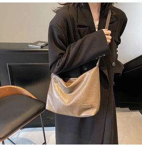 Dettaglio della borsa tote taupe in pelle martellata indossata da modella con blazer