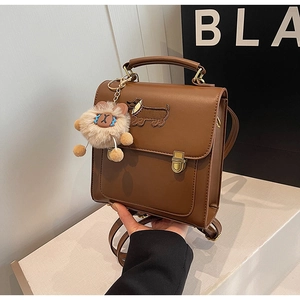 Close-up of retro brown backpack with dachshund embroidery and plush charm on PU leather