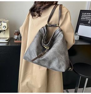 Detail der Vintage grauen Hobo-Tasche mit braunen Lederriemen und Metallbeschlag-Detail