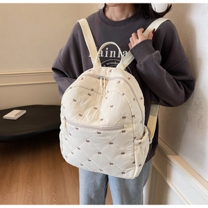 Détail du sac à dos matelassé crème avec broderies nœuds bruns et fermeture éclair