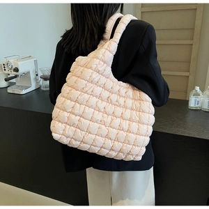 Close-up of a light pink quilted puffer tote bag made of glossy nylon fabric