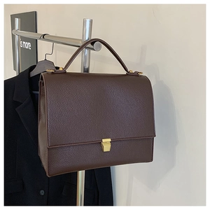 Detail of dark brown pebble leather bag with golden buckle and top handle