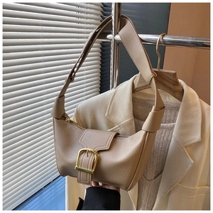 Dettaglio borsa hobo in pelle beige con fibbia dorata e tracolla ampia annodata