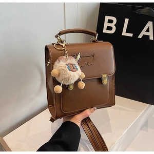 Detail of vintage brown leather backpack featuring dachshund embroidery and plush charm