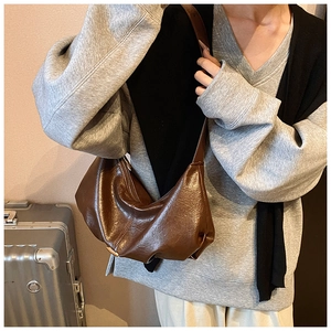 Vue détaillée de la texture en cuir marron plissé et du zip du sac rétro en demi-lune