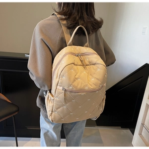 Détail du sac à dos beige matelassé avec motifs nœuds et fermetures éclair