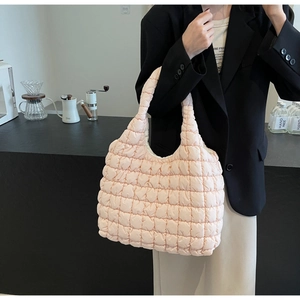 Detailed view of pink quilted tote bag with square pattern on model in cafe