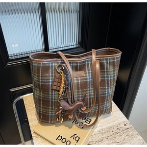 Detailed view of checkered tote bag with brown leather dog and chocolate bar pendants