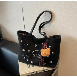 Detail of black suede tote bag featuring cartoon bear print and plush bear charm