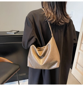 Dettaglio della borsa tote in ecopelle marrone con pieghe e logo in metallo lucido