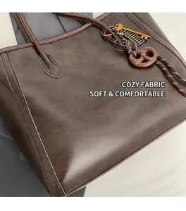 Close-up of vintage brown tote bag leather texture with golden abacus and pretzel pendant