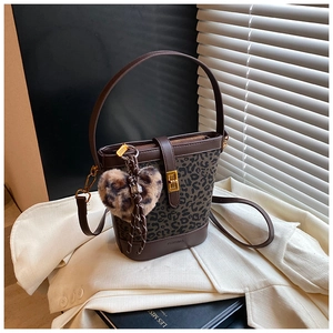 Detail of leopard print bucket bag featuring a plush heart charm and dark brown handle
