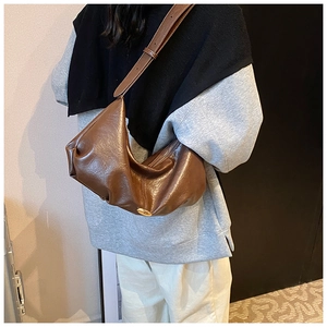 Détail du sac bandoulière marron plissé en similicuir avec ornement doré et longue sangle