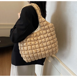 Detailed side view of beige quilted tote bag showing soft texture and strap scale