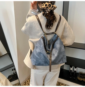 Detail eines blauen Vintage-Rucksacks mit braunen Kunstlederriemen an einem Modell