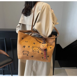 Detail of vintage brown suede tote bag with cartoon embroidery and plush bear pendant