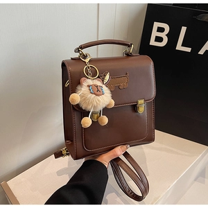 Detail of dark brown vintage backpack with dachshund embroidery and a plush doll charm