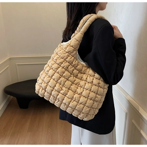 Close-up of beige quilted puffy tote bag with soft texture carried by model in casual style