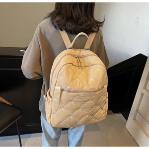 Vue détaillée du sac à dos matelassé beige avec motifs nœuds et multi-poches
