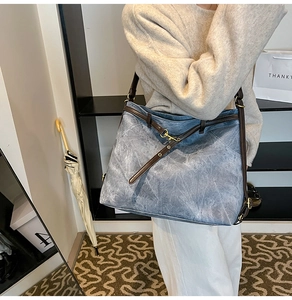 Detail showing vintage washed blue tote with brown leather strap and golden metal buckle