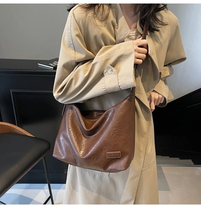 Dettaglio borsa tote marrone vintage con texture in pelle plissettata e logo del brand