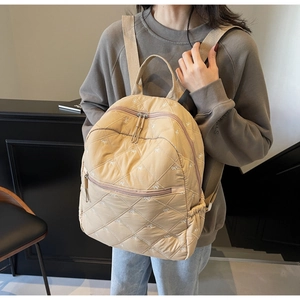 Détail du sac à dos matelassé kaki clair avec broderie papillon blanche et poche zippée