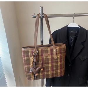Detail of plaid tote bag featuring a leather dachshund charm and chocolate pendant