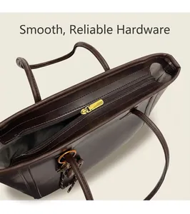 Close-up of golden zipper hardware and stitching on a dark brown leather tote bag
