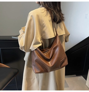 Dettaglio della borsa hobo in morbida pelle marrone con texture naturale e tracolla indossata