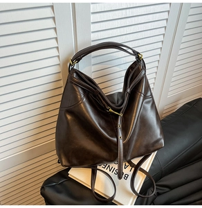 Detail der braunen Vintage-Tote-Tasche mit glänzendem Lederfinish und Goldbeschlägen
