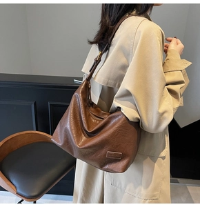 Dettaglio borsa hobo in pelle testa di moro con trama vintage su trench beige