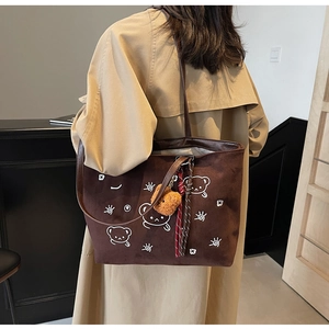 Detailed close-up of dark brown suede tote bag featuring white cartoon bear prints