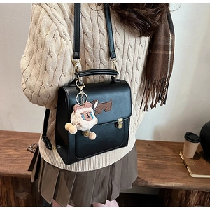 Detail of vintage black faux leather handbag with dachshund patch and plush bear charm