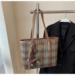 Detail of British vintage plaid tote bag with teddy bear tag and leather dog charm