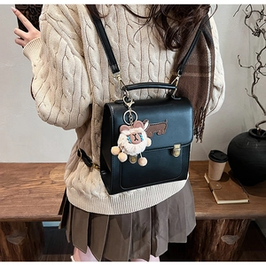 Close-up of black retro backpack with dachshund embroidery and cute plush charm detail