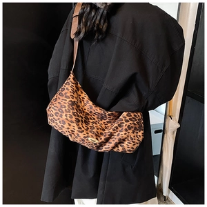 Vue détaillée du sac bandoulière léopard avec fermoir doré sur manteau noir