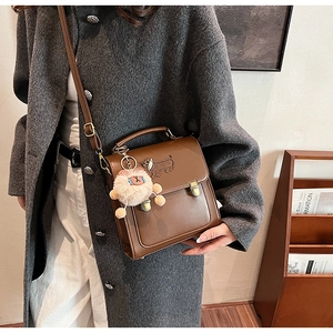Detail of vintage brown leather backpack with dog embroidery and plush keychain charm