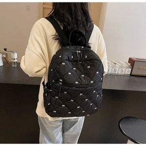 Détail du sac à dos matelassé noir avec broderies de nœuds blancs et zip