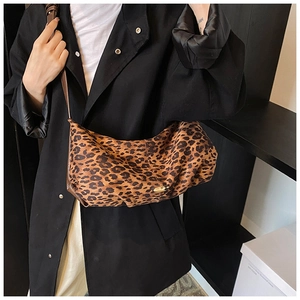 Détail du sac à main léopard avec boucle dorée sur un mannequin en trench-coat noir