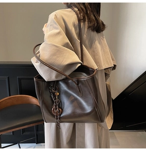 Brown leather tote bag featuring a woven pendant and large capacity for daily commuting