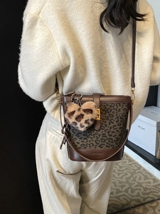 Vintage leopard bucket bag with leather trim and heart charm shown on model back