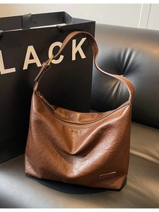 Borsa hobo vintage in pelle PU marrone scuro con tracolla su divano in pelle