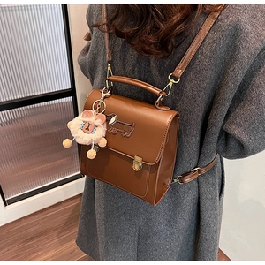 Brown vintage leather backpack with dachshund patch and plush charm shown on model