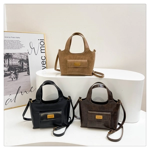Détail de sacs cabas rétro en cuir mat kaki, noir et marron avec finitions métalliques