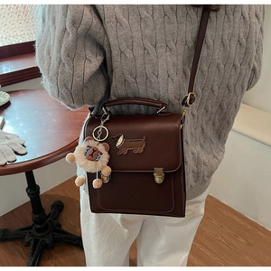 Detail of vintage brown leather backpack with golden buckle and cute plush charm