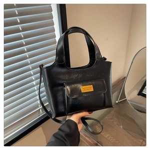 Vue détaillée du sac à main en cuir brillant noir avec plaque métallique dorée de mode