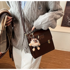 Detail of vintage dark brown faux leather bag with dachshund patch and plush charm